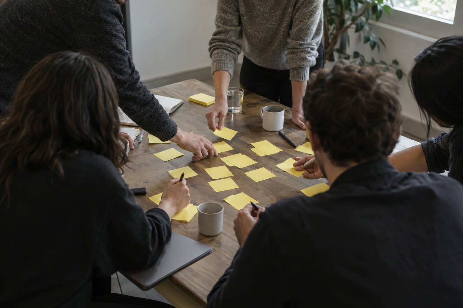 A small team arranging sticky notes around a table